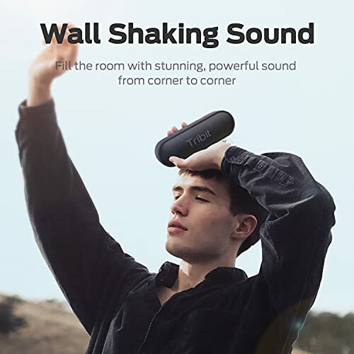 Person holding Tribit speaker outdoors with text 'Wall Shaking Sound'.