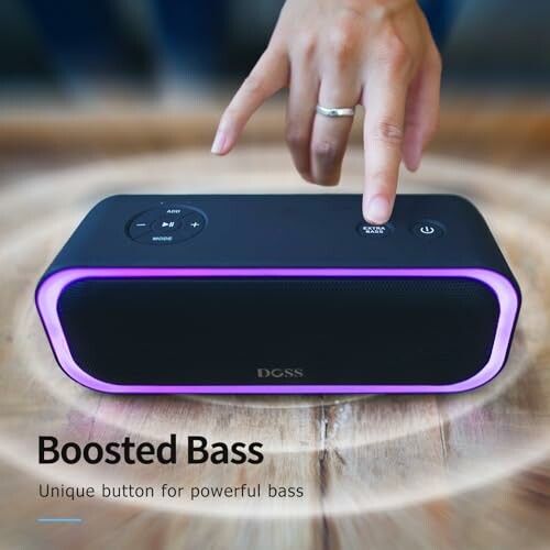 Hand pressing button on wireless speaker with purple lighting.