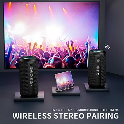 Wireless stereo speakers with smartphone displaying concert scene.
